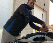 Young man working on engine of car.