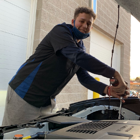Young man working on engine of car.