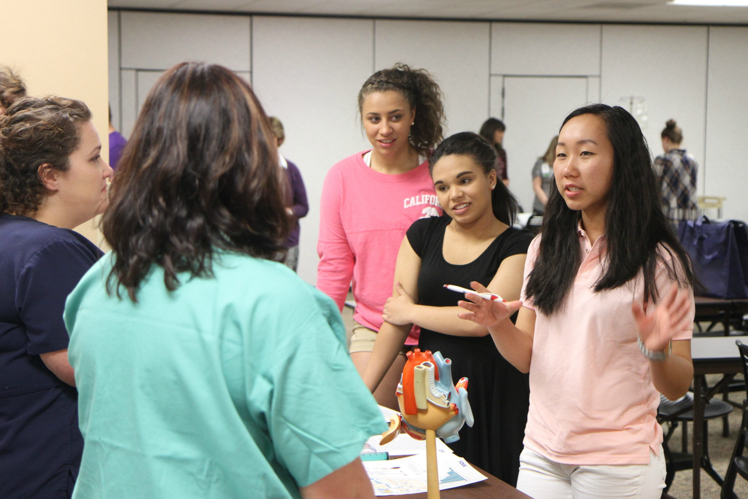1 Three female youth talking to a healthcare company at a career fair.